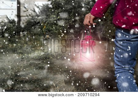 Woman hand with latern. Christmas background with snow in outdoor