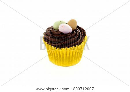 Easter cupcake with chocolate frosting and chocolate Easter eggs on white background with copy space.