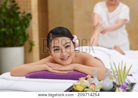 Beautiful Vietnamese young woman enjoying relaxing feet massage as a part of spa procedure