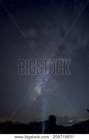 Long exposure and High ISO shot of A man looking and lighting to star and milky way over the mountain at night.