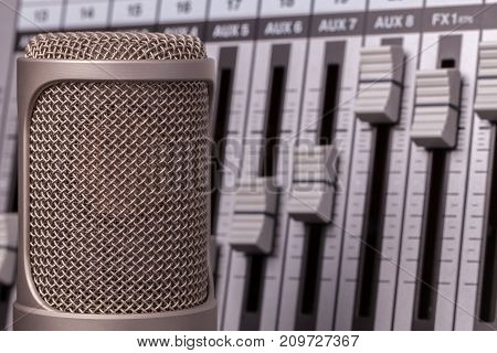 Professional recording microphone with studio audio mixer in the background. Vocal song recording equipment in close up.