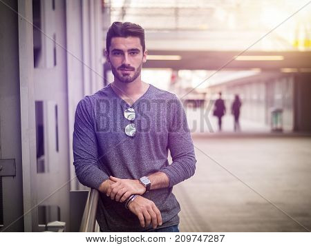 Attractive young bearded man portrait in urban setting, looking at camera