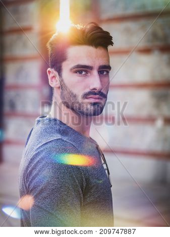 Attractive young bearded man portrait in urban setting, looking at camera