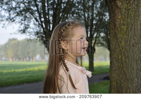 Child laughing and looking away on a beautiful morning near a grassfield