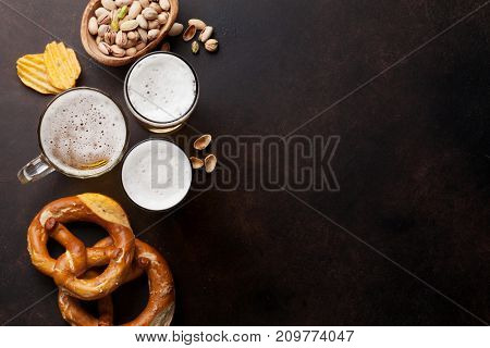 Lager beer and snacks on stone table. Nuts, chips, pretzel. Top view with copy space