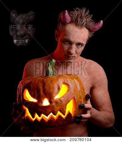 Man in the guise of the devil and with a pumpkin in his hands. On the holiday of Halloween