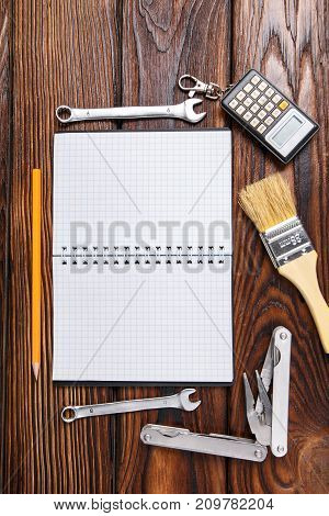 Set of old hand tools and notepad on wooden table