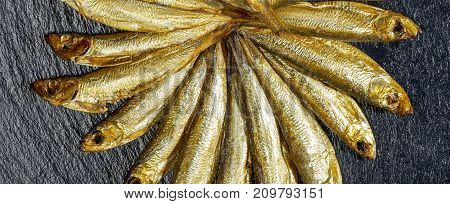 arrangement with lots of fresh smoked sprats on dark stone slab