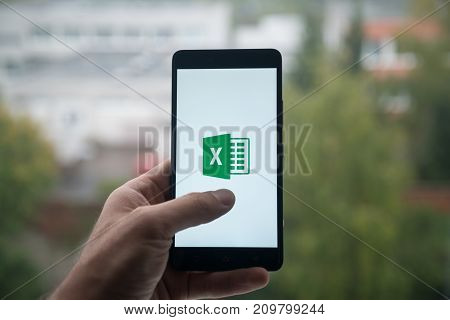 London, United Kingdom, october 3, 2017: Man holding smartphone with Mi rosoft office excel logo with the finger on the screen