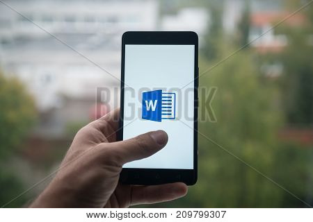 London, United Kingdom, october 3, 2017: Man holding smartphone with Microsoft office word logo with the finger on the screen