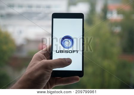 London, United Kingdom, october 3, 2017: Man holding smartphone with Ubisoft logo with the finger on the screen