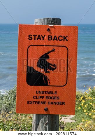 Unstable Cliffs Warning Sign on wooden post over cliff near ocean side