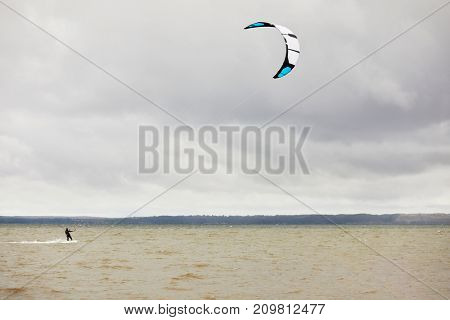 Kitesurfer on lake on cloudy windy day.