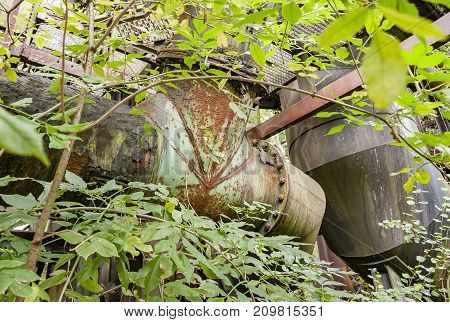 rotten industrial scenery partly covered by vegetation