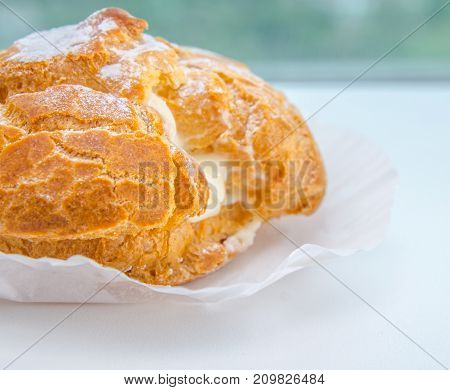 Profiteroles stuffed with pastry cream on white desk in cafe