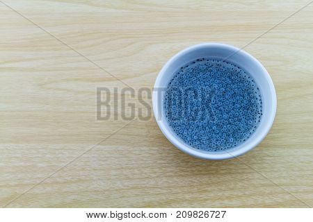Sweet basil in white cup on wooden background.