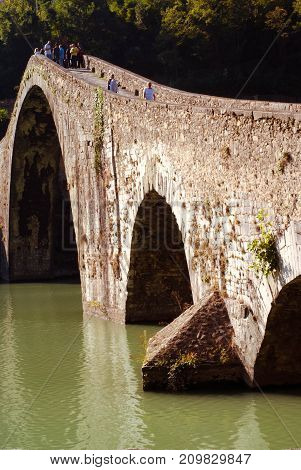 people walk on Maddalena bridge aka Devil bridge in tuscany Italy