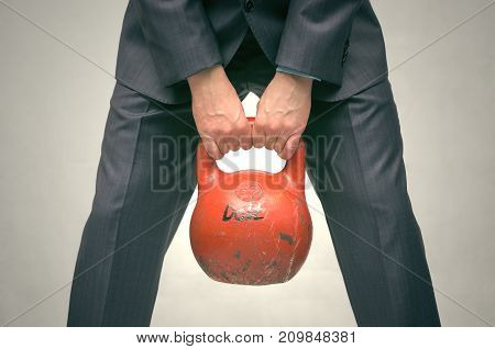 Debt. Debentures. Business man holding in his hands kettlebell with DEBT inscription isolated on grey background.