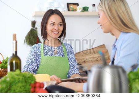 Two young happy woman making cooking in the kitchen. Friendship and culinary concept.