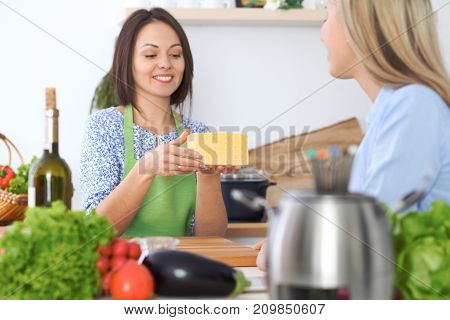 Two young happy woman making cooking in the kitchen. Friendship and culinary concept.