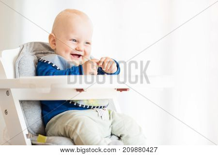 Baby boy eating bread and cucumber with BLW method baby led weaning. Vegetarian kid eating lunch.