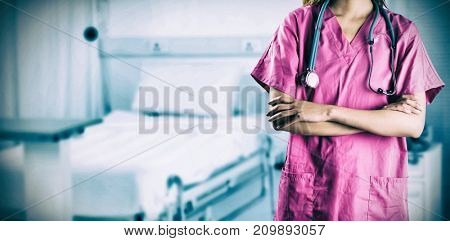 Asian nurse crossing arms against defocused image of empty bed