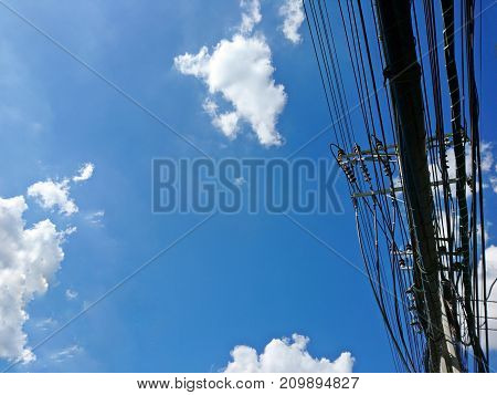 Electric pole of the high voltage electric wires and communication cable on blue sky background