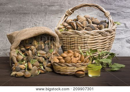 Almonds over a rustic wooden board. Rustic sack and basket. Nutcracker and almond oil.