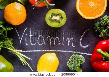 Fruits and vegetables rich in vitamin c with white word inscription by chalk.