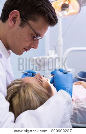 Close up dentist examining woman with dental equipments at medical clinic