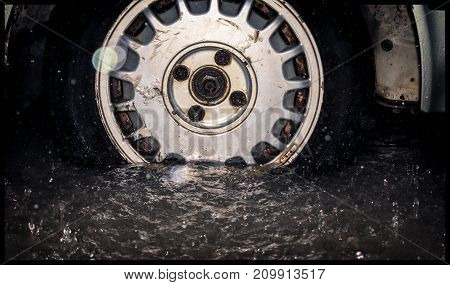 Old rusted wheel and tire from an old car getting inundated by flood in heavy rain fall