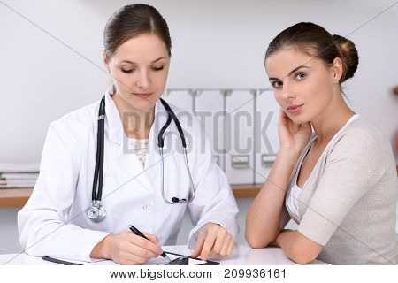 Doctor and  patient  sitting at the desk. The physician or therapist makes a diagnosis. Health care, medicine and patient service concept.