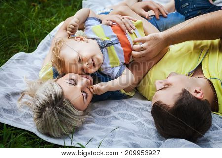 joyful young family resting in city park, lovely couple playing with his little baby, concept happy family