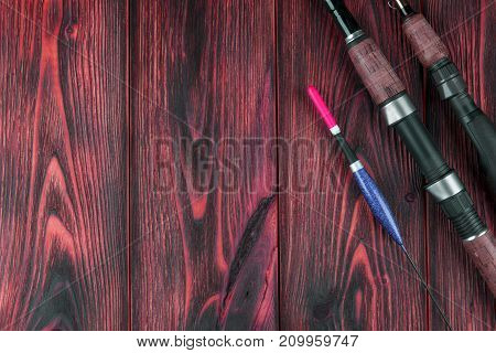 Fishing tackle - fishing rod fishing float and lures on beautiful red wooden background