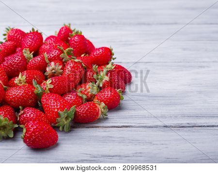 Fresh ripe fruits on a gray wooden table. Sweety red strawberries summer fruits on a gray background. Copy space. Close-up of strawberry. Food concept.