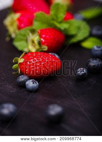 Fresh ripe fruits on a dark wooden table. Sweety red strawberries summer fruits on a dark brown background. Close-up of strawberry. Food concept.