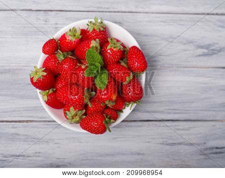 Fresh ripe fruits on a gray wooden table. Sweety red strawberries summer fruits on a gray background. Close-up of strawberry. Food concept.