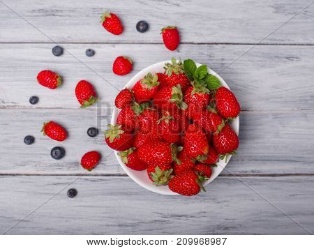 Fresh ripe fruits on a gray wooden table. Sweety red strawberries summer fruits on a gray background. Close-up of strawberry. Food concept.