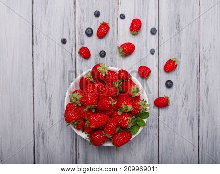 Fresh ripe fruits on a gray wooden table. Sweety red strawberries summer fruits on a gray background. Close-up of strawberry. Food concept.