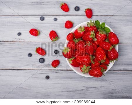 Fresh ripe fruits on a gray wooden table. Sweety red strawberries summer fruits on a gray background. Close-up of strawberry. Food concept.