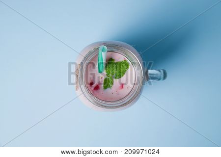Tasty sweet strawberries and fruits yogurt in mason jar on a blue background. Healthy organic drink. Copy space. Close-up of drink. Food concept.