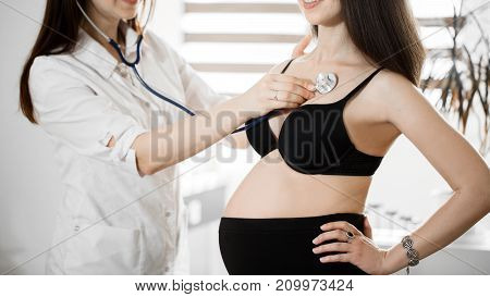female medicine doctor holding stethoscope to pregnant woman standing for encouragement, empathy, cheering, support, medical examination. New life of abortion concept