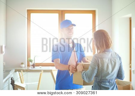Smiling Delivery Man In Blue Uniform Delivering Parcel Box To Recipient - Courier Service Concept. S