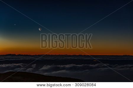 Morning Dark Sunrise With Blue Sky And Golden Yellow Orange Color Above Horizon. Night Lights Of Gra