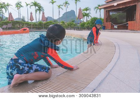 Two Asian Siblings In Playing Together In Water Aqua Park Pool.
