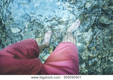 Hiking Outdoors In The Forest: Cut Out Of Male Barefoot Feet In A Shallow River, Fresh Water