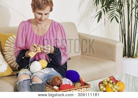 Smiling Aged Caucasian Woman Enjoying Knitting New Skaft With Colorful Whool