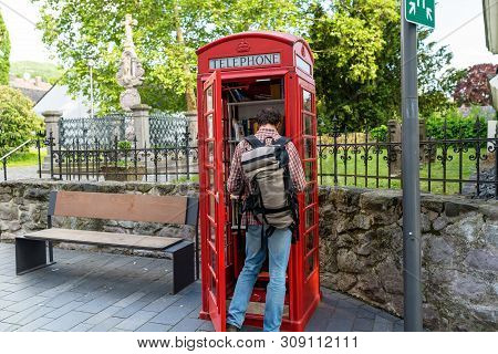 Konigswinter, Germany - 23 May 2019. A Red Telephone Booth For The Free Exchange Of Books. A Man Loo