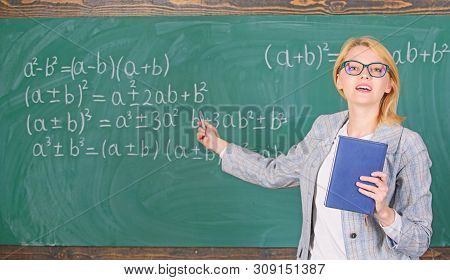 Teacher Smart Woman With Book Explain Topic Near Chalkboard. School Teacher Explain Things Well And 