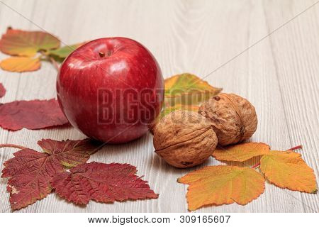 Apple, Walnuts And Dry Leaves On Wooden Boards. An Autumn Still Llife.